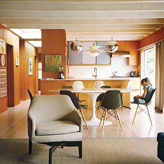 Long Island Found - Photo 8 of 12 - The open-plan living-kitchen-dining area is a repository of design icons, both classic and contemporary. There’s a Louis Poulsen pendant lamp over the Eero Saarinen dining table; Mirror Ball pendants by Tom Dixon over the kitchen counter; and Tab F1 floor lamps from Flos behind the Edward Wormley–designed Dunbar sofa. In the living room, chairs modeled on Jens Risom’s swivel design enable people to face either the sofa or to spin 180 degrees toward the kitchen.