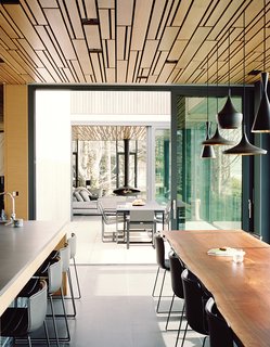 In this Portland home, design firm Made arranged individually carved white-oak planks in a geometric pattern on the ceiling that repeats itself throughout the house. Beat Light pendant lamps by Tom Dixon hang above a custom dining table, also by Made.