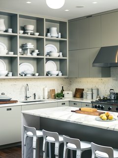 Custom kitchen cabinets designed by Pulltab and fabricated by Maciek Winiarczyk hold mostly vintage ironstone that Geiger has found at flea markets and estate sales over the past 20 years. "I love white," she says, "because I think food always looks better on it." She also collects vintage wooden cutting boards, shown resting against the marble tile backsplash from Stone Source.