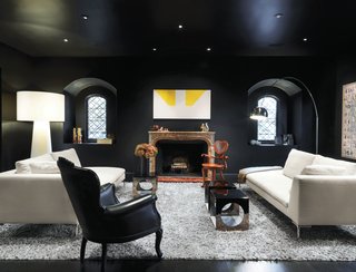 A Traditional Home and an Impeccable Eye - Photo 4 of 8 - Turin embraced the dark in her striking living room—the deep paint is Le Corbusier’s 4320J from Les Couleurs Suisse. An iconic Arco lamp by Achille and Pier Giacomo Castiglioni for Flos, Charles sofas by Antonio Citterio for B&B Italia, an Extra Big Shadow floor lamp by Marcel Wanders for Cappellini, and a painting over the mantel by Martin Barré shed a little light.