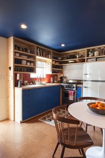 A Modern Beachside Trailer Home in Malibu - Photo 4 of 7 - The kitchen cabinetry echoes the new blue ceiling. The brick tile is from Heath Ceramics, as is the dinnerware. Behind the Viking stove is powder-coated corrugated metal ("Very trailer," says the designer). The refrigerator is from Big Chill. On the table is a bowl by Victoria Morris.
