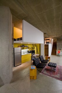 "The kitchen didn’t really have a home," says Colkitt. His solution was to build a sleeping loft directly above it, giving the kitchen some architectural congruity, and implement recessed lighting into the dropped ceiling—also the underside of the floor of the sleeping loft. Like the reading loft, the sleeping loft is open on both sides to bring in light and air, with a single ladder leading up to it. "The sleeping loft ‘fold’ is a complement to the reading loft ‘fold’—they balance each other out," says Colkitt. 
