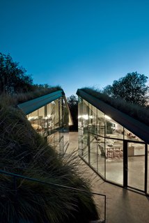 Edgeland House, built on a cliff-top lot in Austin by architect Thomas Bercy for lawyer and writer Chris Brown, is topped by a living roof to help it blend into the landscape. The concrete, steel, and glass house is divided into two distinct public and private halves.