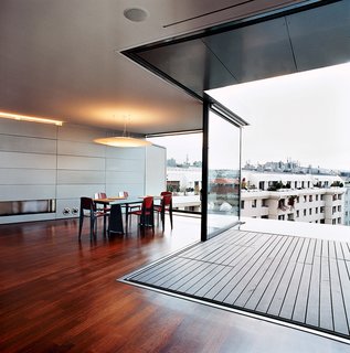 The Penthouse Has Landed - Photo 4 of 16 - The engineering of House Ray 1’s load-bearing structure was extremely complex. Since the house had to be built on top of an old building, the architects opted for lightweight steel skeleton construction. The living/dining area has sliding glass walls that open to the back terrace and pool.