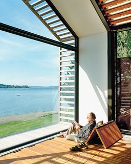 The Trues host parties in the glass-walled structure, located steps from their vacation home, or they escape to it to catch some rays and read a book. Bill reclines on cushions hidden under the reclaimed-fir floorboards that are propped up with Sugatsune hinges.