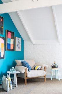 A Wilfred armchair by Jardan is accented by pillows from Penelope Durston and L.O.T.S. Artwork is by Rachel Castle, and walls are painted in Waterworld by Dulux. Photo by Phu Tang.