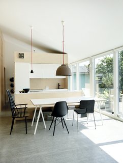 20 Best Modern Kitchen Counters - Photo 11 of 20 - An imaginary axis divides the floor plan down the middle, with the open-plan living room and kitchen to the south and three bedrooms to the north. In the dining area, a freestanding island hides appliances and piping, while also providing counter space. Floor-to-ceiling windows make the outside deck and garden feel like an extension of the interior.