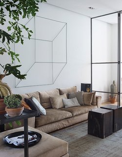 In the main living area of Frank Nederhof’s renovated Amsterdam flat, a geometric sculpture by Antonino Sciortino hangs above an Erik Kuster sofa. The coffee tables are made from fossilized wood so heavy that each one requires two people to lift it.