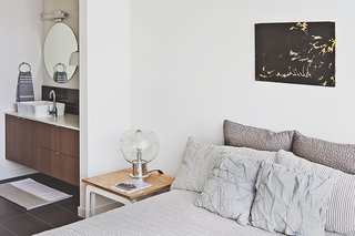 Bowie designed the nightstand, which acts as a prime perch for a vintage lamp her parents purchased in the Netherlands. The wall paint throughout the unit is Eider White by Sherwin-Williams.