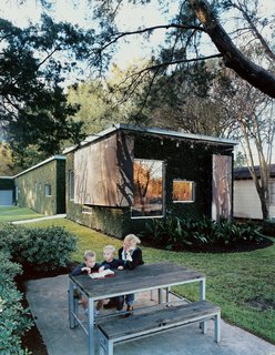 The family takes full advantage of their sylvan yard, Sarah Baird and her children Bo and Sky read a book out on the picnic table.