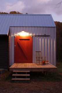 The red barn door on a sliding track door is an icon, built from salvaged pine from the original farmhouse. Image courtesy Chad Everhart Architect.