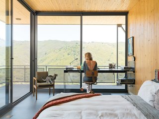 50 Modern Homes With Floor-to-Ceiling Windows - Photo 2 of 50 - Architect Bruce Bolander made the most of a limited footprint in a house he designed in a Malibu canyon. With the small bedroom being unable to accommodate any "normal" size desk, the architect designed a very thin custom steel desk where resident Heidi Wright works. The floor-to-ceiling sliding glass doors from Metal Window Corporation open the entire corner of the room up to the outdoors.