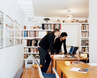 Lit by the skylight and an Artemide ceiling lamp, Schenk and Ngai consult laptops on mid-century Heywood Wakefield desks, which Fernandez salvaged from a Harvard junkyard and then restored.