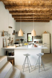 Jamaica barstools by Pepe Cortès for Knoll and two Ikea pendants pair nicely with the plaster walls, restored wooden beam ceilings, and polished cement floors in the kitchen.