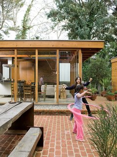 Compound Addition - Photo 9 of 12 - The courtyard acts like an outdoor living room, where the Arnolds’ daughter, Josie, plays freely, safe from nearby traffic. The family dines here most of the year at the custom-designed wood-and-steel table. The picnic table set reappropriates the century-old eucalyptus tree that once grew on the site.