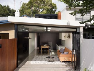 The Alexandria House uses a material palette of polished concrete floors, ruddy hardwood accents, and smooth white plaster. Black covers entire walls in the living room and kitchen and threads throughout the home, popping up everywhere from the iron railing outside to the decorative picture frames inside.