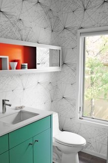 In the new powder room, Jill Malek wallpaper adds graphic punch to custom cabinetry.