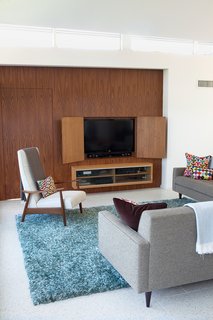 Architect Cindy Black chose terrazzo tile flooring by Concrete Collaborative over higher-priced competitors because it’s a "little more polished looking". Before installing the material, the builder had to completely re-level the concrete subfloor, which had settled over time leaving a two-inch gap on one side. The sofa is from Room & Board, and the custom walnut media wall was designed to match the kitchen built-ins.