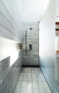 When this Toronto couple remodeled their Tudor home, they went for a material-rich bathroom design. The standing shower is set off by etched-glass panels supported by stainless-steel hardware. There is no threshold; instead, the tile within the shower zone slopes down very slightly to a floor trough with a custom stainless-steel grille. Along the wall, a Corian shelf—"the longest soap dish in the world," jokes the homeowner—runs the length of the space.