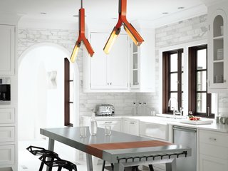 Overhead lighting customized by Rich Brilliant Willing in a pert orange accents the primarily black-and-white interior scheme.