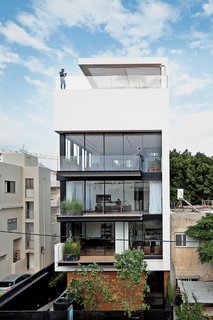 50 Modern Homes With Floor-to-Ceiling Windows - Photo 15 of 50 - Tall and surprisingly open, the Tel Aviv Town House by Pitsou Kedem Architects continues in the tradition of its Bauhaus-inspired neighbors with a white facade and black window frames. Six stories high, crowned with a pool, and with a direct lineage back to the Bauhaus, the house manages to both embrace and provide refuge from the teeming Israeli city.