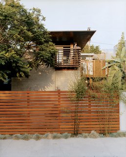 Trellis-like balcony railing cue the exposed timber frame extending over the house. The balcony and fence are made from sustainably harvested ipe wood.
