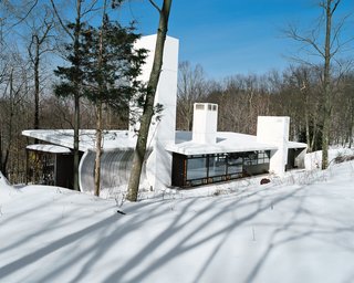 "If you look closely at the concrete wall, the curvature is based on one really simple formal move," says Massie. "In front, the roof is about 11 feet high, and in back, about 9 feet. If you could imagine just pinching the back of the building, that linear distance would have to go somewhere, hence the curve." That arc continues inside as the wall nearest to the guest sleeping area. "It’s really interesting to feel that wall dimpling toward you," says Wooten. "It changes as you walk from the bedroom to the guest bath—it starts with a dramatic curve and gradually flattens out."