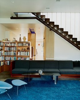 Solar Inspiration - Photo 6 of 8 - A built-in sofa with Design Tex upholstery marks the boundary between the two-level addition and the bungalow. Leading up to the master bedroom, a perforated metal staircase, lit from above, casts a Sigmar Polke–like shadow grid on the concrete floor.
