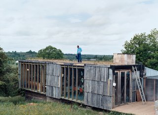 Emerald in the Rough - Photo 4 of 10 - Atop a living module that contains a kitchen and eating and living areas, Dominic Stevens waters the sod roof, which, like the rest of the house, is a perennial work in progress.