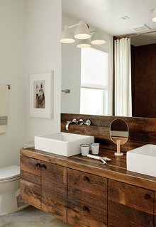 Builder Luke Gilligan of Gilligan Development used reclaimed oak planks from a deconstructed barn to create the bathroom’s millwork. To achieve the rugged look, he sanded and wire-brushed the wood, then applied a clear stain. The sinks are from Duravit’s Vero line and the cabinet pulls are from Top Knobs.