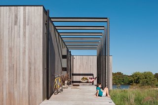 Take it Outside With These 11 Spring-Friendly Deck Spaces - Photo 4 of 11 - A family home on Australia’s Mornington Peninsula is built to blend in with its lakeside setting. Harper sits on the porch just off the entrance. James notes that the children spend their time "swimming in the dam, feeding the chickens, and riding their ponies or bikes. It’s really just the simple stuff that we had when we grew up in the late ’70s and ’80s."