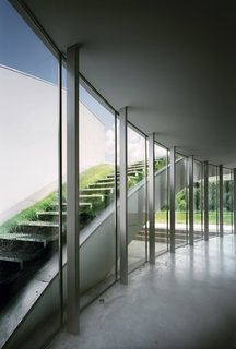 The expansive open-air living room on the first floor is framed with a curving wall of windows. The glass wall works as an outdoor atrium looking out on an exposed <br><br>sod-covered staircase and allows the room to be bathed in natural light.