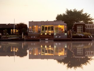 At the rear of the house, bleacher-style steps mitigate the steep grade down to <br><br>the water; the boathouse tucks in on the right.