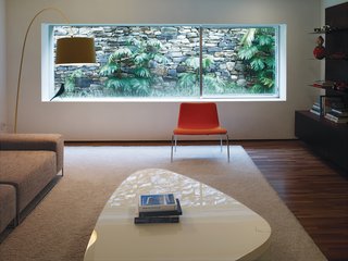 In the media room, the saturated colors of the Paper chair by Piero Lissoni for Cappellini and the Twiggy floor lamp by Foscarini contrast with the wide-screen view of the back garden.