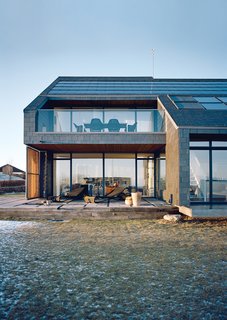 While the slate-clad northern facade has few windows and a steeply pitched roof, the southern facade is dominated by glass with the solar-panel-clad roof strategically angled to catch the sun.