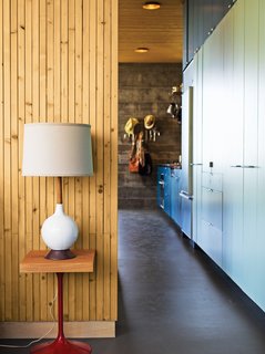 A colorful, laminate-clad wall of storage stretches seamlessly from the kitchen—where it holds a full-size built-in Sub-Zero refrigerator and freezer, a Miele dishwasher, a Bosch cooktop, and a tiny convection oven—to the bedroom, where it contains the couple’s clothing, shoes, and linens.