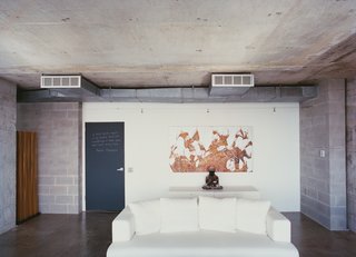 The words of the prophets are written on the chalkboard-paint-coated door to Hill's apartment. A painting by Mark Flood hangs behind a plaster Buddha on a chest from Cassina. The Ligne Roset cotten sofa was bought on sale.