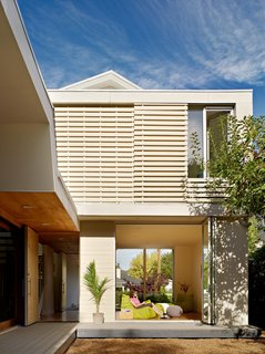 Large screens on the second story windows are a low-tech way to protect the interior from the sun's blistering rays, but still allow natural light to flow inside. In the family room, Melissa reclines on a Togo sofa by Ligne Roset with a favorite book in hand.
