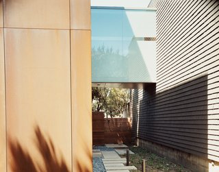 This Surfer's Beach House is More Than It Seems - Photo 2 of 13 - The frosted-glass bridge unites the original 1950s structure (right) to the new addition, which is sheathed in Cor-ten steel panels.