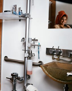 In the bathroom, the Stylo bar by Alu eliminates the need for space-eating cabinets by creating a vertical tower of platforms on which all the hygienic essentials rest. Generally used in retail displays, the Stylo stretches from floor to ceiling; platforms branch off at various intervals, creating resting spots for toilet paper, shaving gear, toothpaste, soap, and other necessities. The tub is built up from a rubberized plaster by Miracote and finished off with a woven fabric mesh and final layer of All-in-One coating, popular in prisons for its low price and durability.