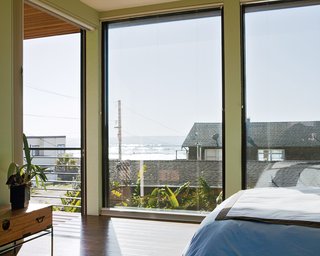 Floor-to-ceiling windows in the bedroom create the sensation of being outside, as if the entire house is one platform deck strategically shielded from the elements.