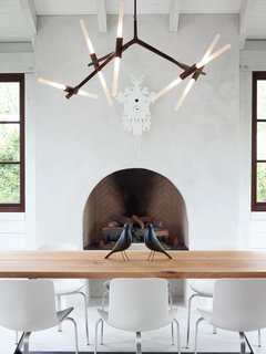 The home’s informal dining space has a slightly rustic feel, sporting bronze and wood in the form of a Lindsey Adams Adelman chandelier for Roll & Hill and a table by Terry Dwan, mixed with folk-art touches like the Eames House Birds and a cuckoo clock from Diamantini & Domeniconi. The PK8 chairs from Republic of Fritz Hansen were designed by Poul Kjærlholm and sourced from Kuhl-Linscomb in Houston, Texas.