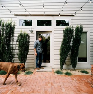 From the side door of his restored two-bedroom bungalow, Dollahite watches his<br>dog West inspect the newly installed low-maintenance landscaping and brick patio.