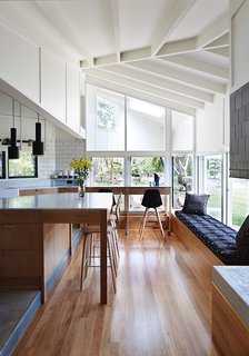 Above, the architects used blackbutt wood for the flooring and Whisper White paint by Dulux throughout the interior. An A110 Hand Grenade Pendant Lamp by Alvar Aalto for Artek hangs above the white Carrara marble-topped island.