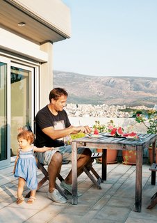 Odd Angles Don't Stop This Apartment's Transformation - Photo 5 of 8 - Vassiliou and Angeliki tuck into watermelon slices on a patio off the master bedroom. The terrace offers views of Mount Lycabettus, whose peak towers 745 feet above Athens, and the city itself, which splays out toward the mountains in the distance.