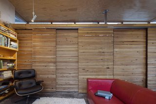 Inside the studio, sliding fir screens hide storage, utilities, and a bathroom. The ceiling and wall panels are plywood, the floor is radiant heated concrete. An Eames lounge chair from Herman Miller mingles with an IKEA sofa.