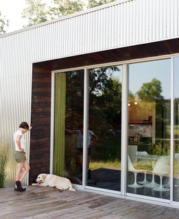 Out on the deck, Pascal enjoys some relaxed time with their dog, taking a breather in a bit of shade while sun streams across the meadow.
