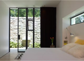 Shielding the bedroom from the courtyard, a black curtain affords privacy while the slotted window above the bed ensures that even when privacy is wanted, the room is bathed in light.