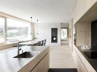 A Simple Gabled House Features an Intricate Latticework Shell - Photo 3 of 10 - Contrasting with the densely organized upper floor, the lower one features one main open area for cooking, eating, and living that spans the building's entire depth. Pendant lamps by Supermodular hang above the dining table.