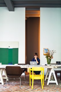 With the help of architect Bart Lens, Veerle Wenes and Bob Christiaens merged a 19th-century building with a 1970s one to create a combined home and art gallery in Antwerp. In the dining room downstairs, Wenes entertains family, friends, and gallery visitors. The yellow chair is by Jens Fager.